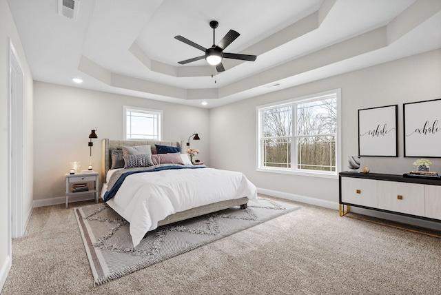 carpeted bedroom featuring a tray ceiling and ceiling fan