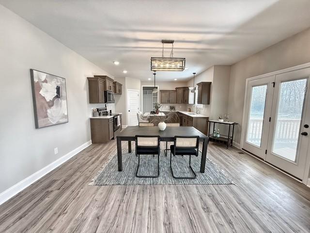 dining space featuring baseboards, wood finished floors, and recessed lighting