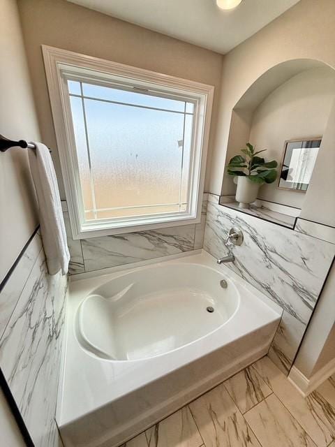 bathroom with marble finish floor and a bath