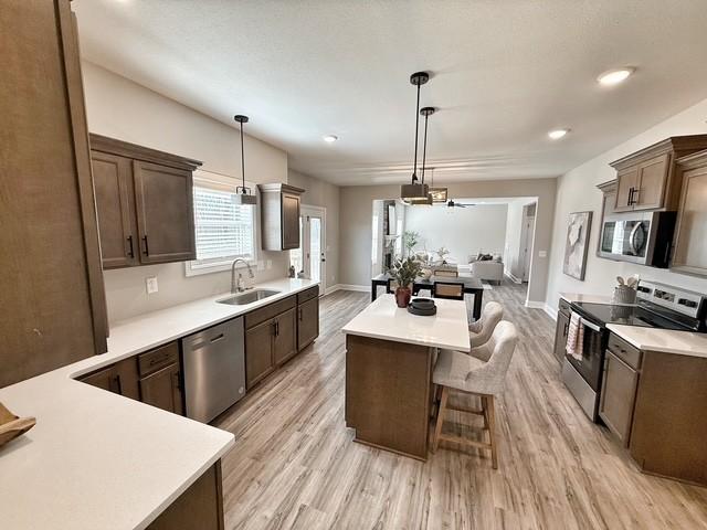 kitchen featuring light countertops, stainless steel appliances, a sink, and a kitchen breakfast bar