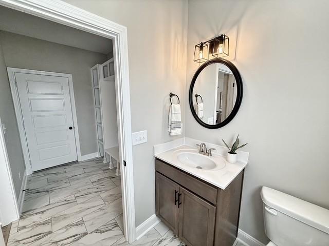 bathroom with marble finish floor, baseboards, vanity, and toilet