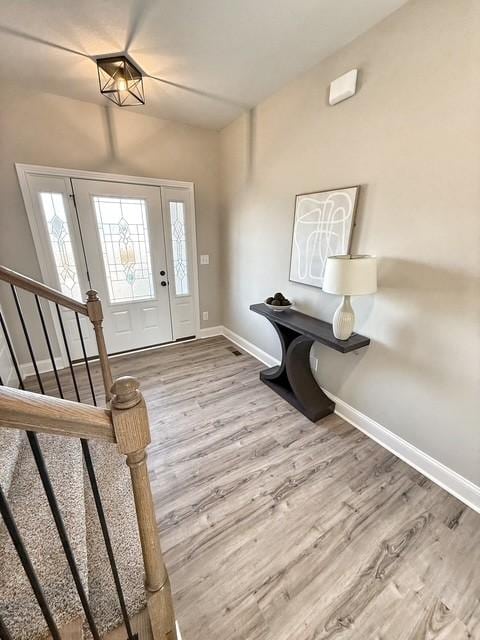 foyer entrance featuring stairway, baseboards, and wood finished floors