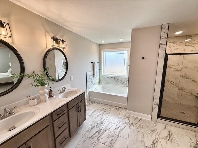 bathroom with marble finish floor, a garden tub, a sink, and a stall shower