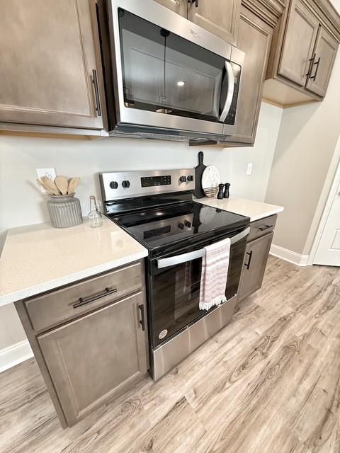 kitchen featuring stainless steel appliances, light countertops, light wood-style floors, and baseboards