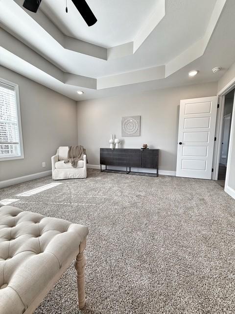 living area with recessed lighting, carpet floors, a ceiling fan, baseboards, and a tray ceiling