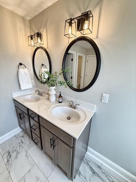 bathroom with marble finish floor, a sink, and baseboards