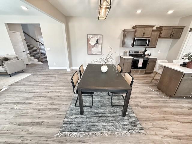 dining room featuring light wood-style floors, recessed lighting, stairway, and baseboards