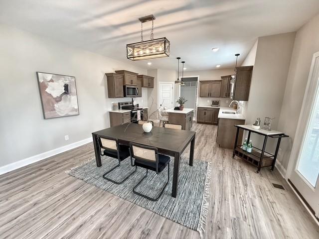 dining space featuring light wood finished floors, visible vents, baseboards, and recessed lighting