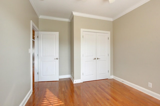 unfurnished bedroom featuring wood-type flooring, ornamental molding, and a closet