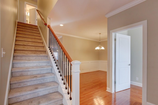 stairs featuring hardwood / wood-style floors, an inviting chandelier, and crown molding