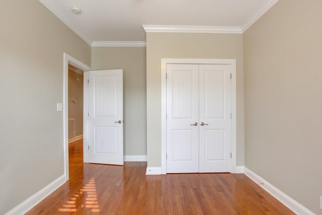 unfurnished bedroom featuring wood-type flooring, ornamental molding, and a closet