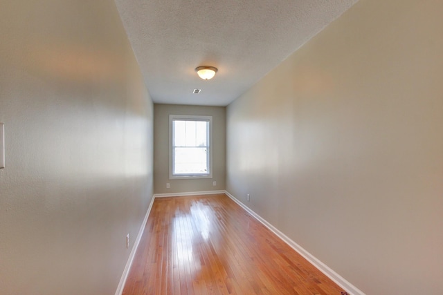 spare room with a textured ceiling and light wood-type flooring