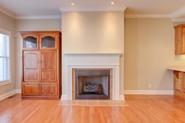 unfurnished living room with light hardwood / wood-style floors, ornamental molding, and a tile fireplace