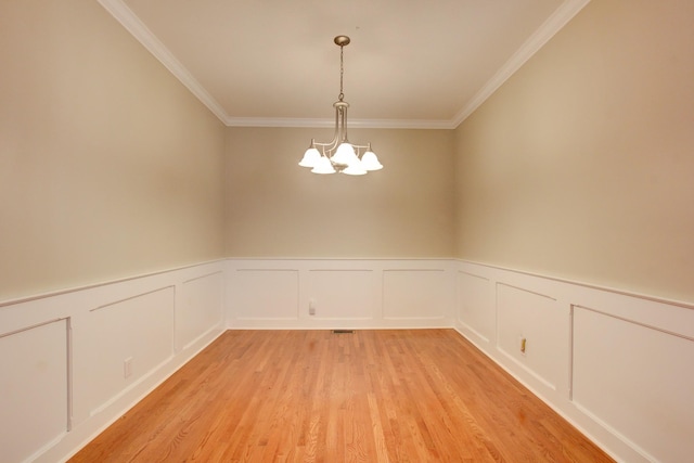 empty room with light hardwood / wood-style flooring, an inviting chandelier, and crown molding