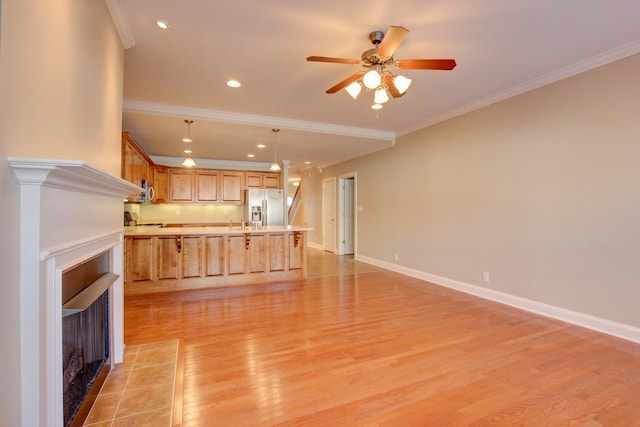 unfurnished living room featuring a tile fireplace, crown molding, ceiling fan, and light hardwood / wood-style floors