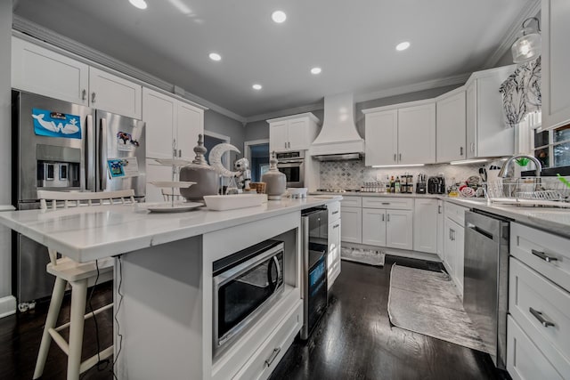 kitchen featuring decorative backsplash, appliances with stainless steel finishes, custom exhaust hood, a center island, and white cabinetry