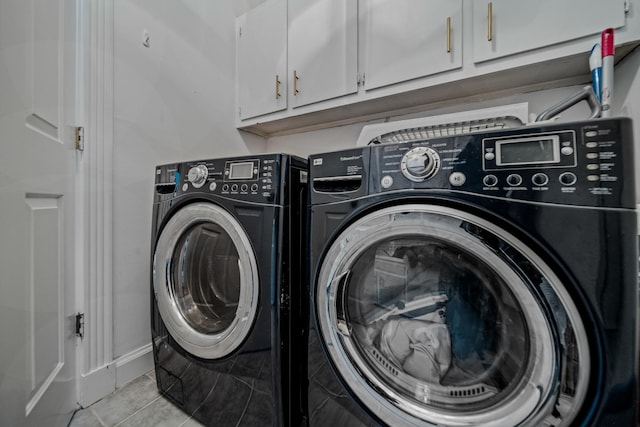 washroom featuring cabinets, light tile patterned floors, and washing machine and clothes dryer