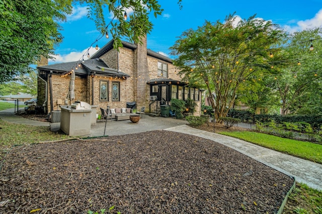 rear view of property featuring an outdoor living space, a patio area, and a sunroom