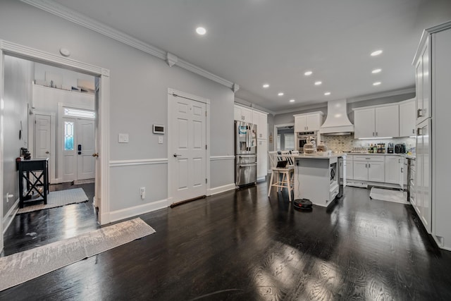 kitchen featuring a kitchen bar, custom exhaust hood, stainless steel appliances, a center island, and white cabinetry