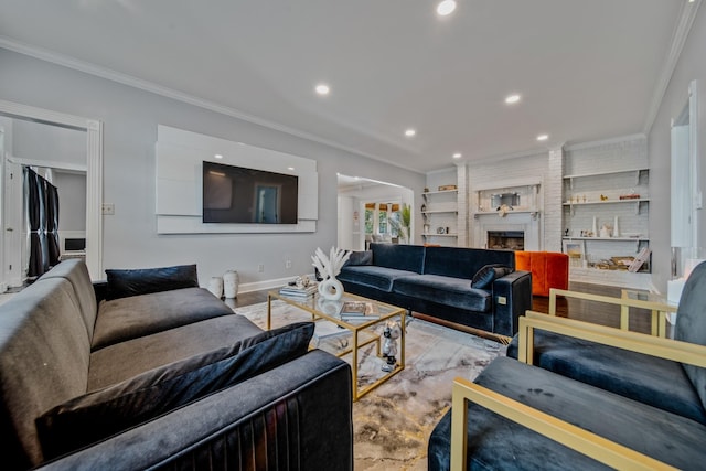 living room with light hardwood / wood-style flooring, built in features, crown molding, and a brick fireplace