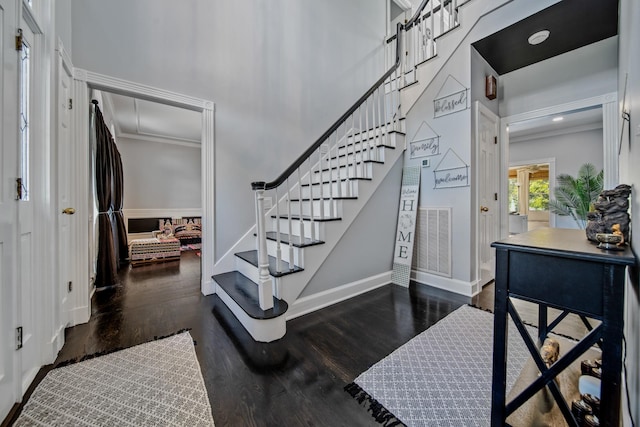 entryway featuring dark hardwood / wood-style floors, crown molding, and a high ceiling