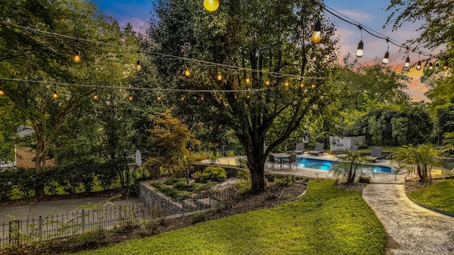 yard at dusk featuring a patio and a fenced in pool