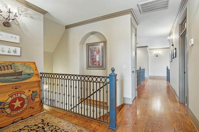 hall featuring hardwood / wood-style floors, lofted ceiling, and crown molding