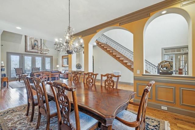 dining area with crown molding, french doors, a chandelier, and hardwood / wood-style flooring