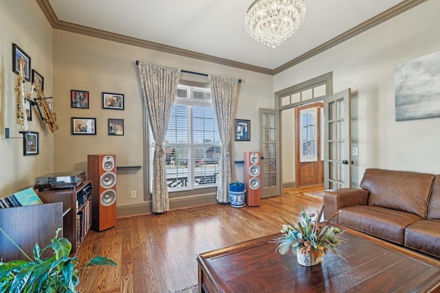 living room featuring french doors, hardwood / wood-style flooring, crown molding, and a notable chandelier