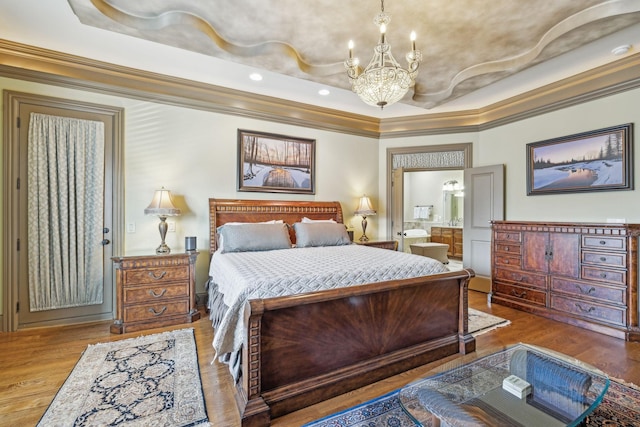 bedroom featuring wood-type flooring, an inviting chandelier, ensuite bath, and crown molding