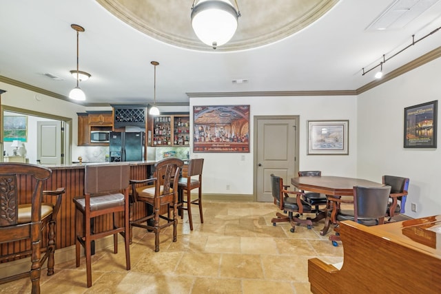 dining space with a tray ceiling, bar area, crown molding, and track lighting