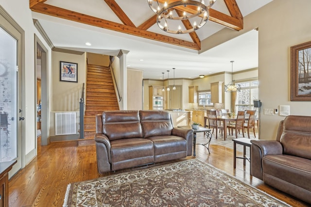 living room with vaulted ceiling with beams, a notable chandelier, wood-type flooring, and ornamental molding