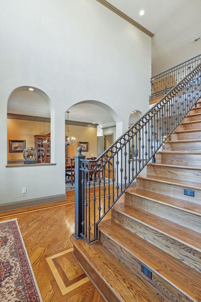 stairway with crown molding and an inviting chandelier