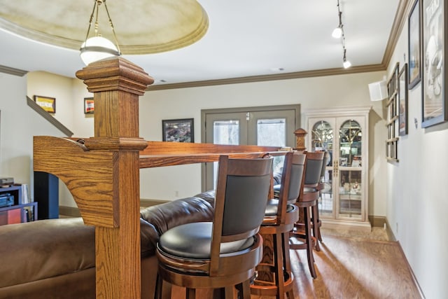 bar featuring crown molding, french doors, rail lighting, and hardwood / wood-style flooring