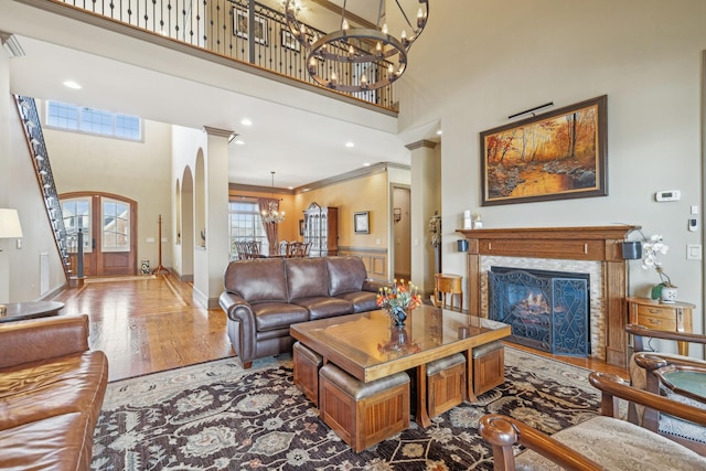 living room with a high ceiling, decorative columns, a chandelier, hardwood / wood-style flooring, and ornamental molding