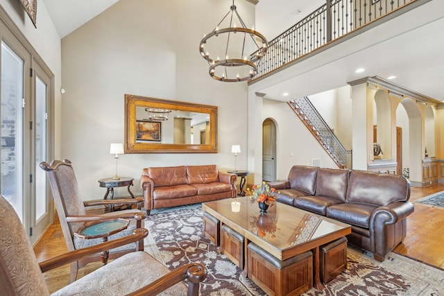 living room featuring hardwood / wood-style flooring, a notable chandelier, and a towering ceiling