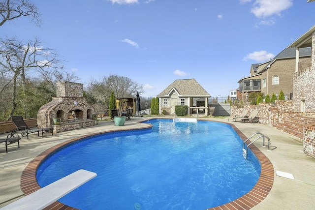 view of swimming pool with a patio area, a diving board, and an outdoor fireplace