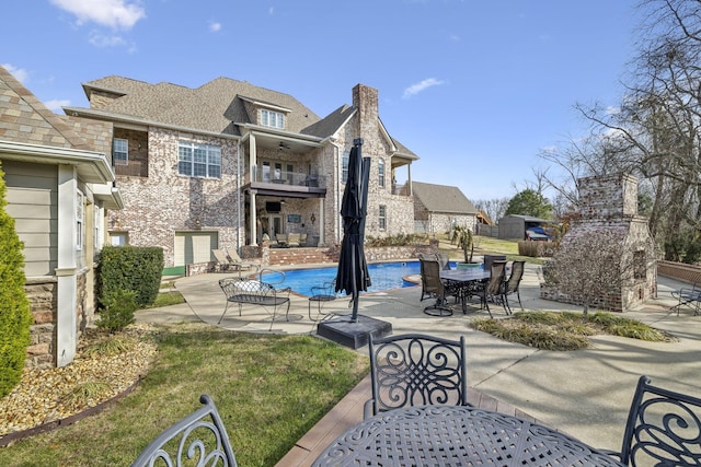 exterior space with ceiling fan, a patio area, a balcony, and an outdoor fireplace