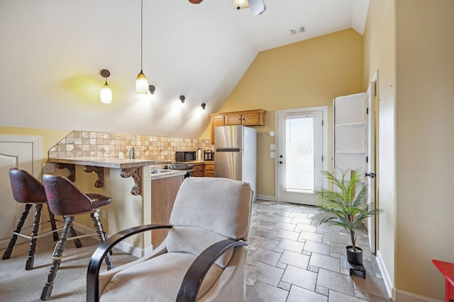 kitchen featuring a kitchen breakfast bar, light tile patterned floors, decorative light fixtures, kitchen peninsula, and stainless steel refrigerator