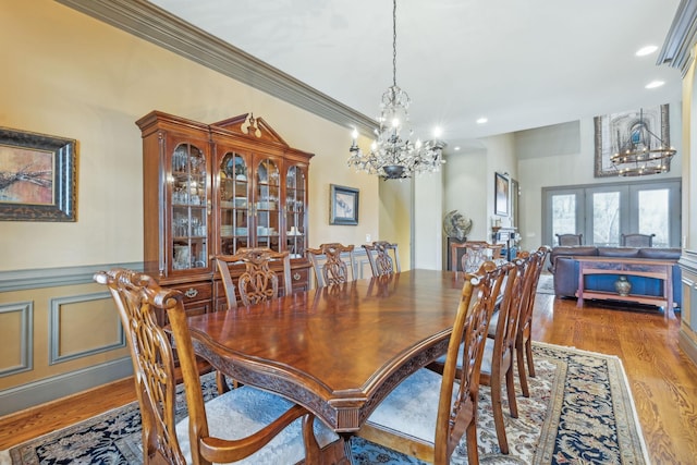 dining area featuring an inviting chandelier, french doors, crown molding, and light hardwood / wood-style flooring