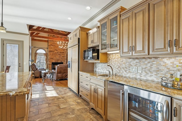 kitchen with pendant lighting, sink, paneled fridge, a large fireplace, and beverage cooler