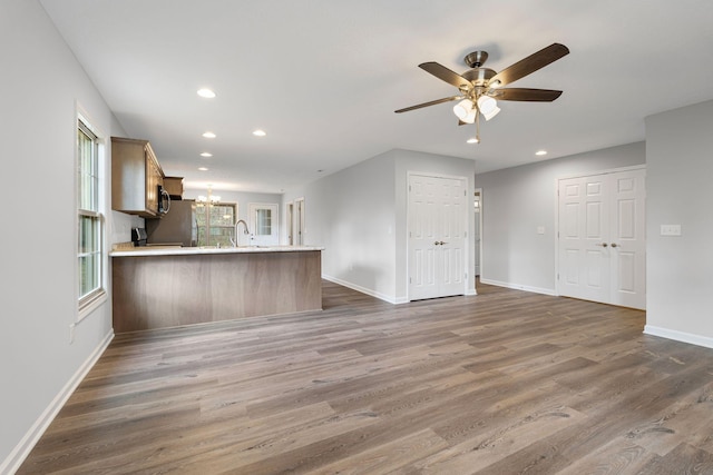 kitchen with ceiling fan with notable chandelier, sink, dark hardwood / wood-style floors, appliances with stainless steel finishes, and kitchen peninsula