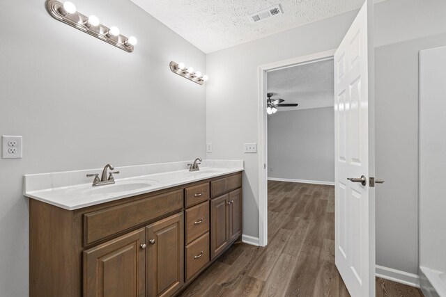 bathroom with vanity, hardwood / wood-style floors, a textured ceiling, and ceiling fan