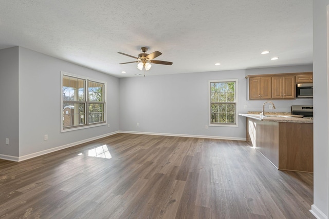 unfurnished living room with a textured ceiling, ceiling fan, and dark wood-type flooring