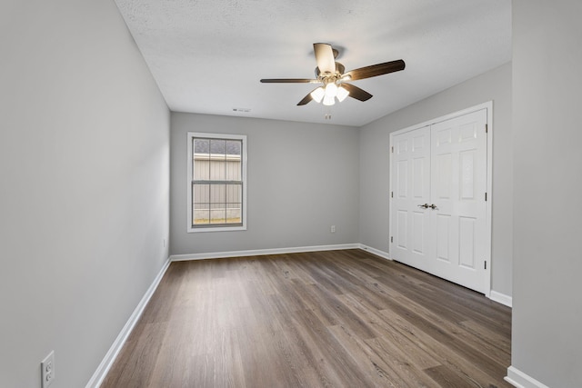 unfurnished bedroom with ceiling fan, a closet, wood-type flooring, and a textured ceiling