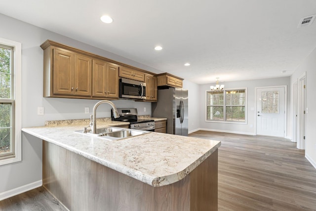 kitchen featuring kitchen peninsula, sink, stainless steel appliances, and a notable chandelier