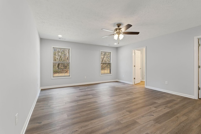 empty room with a textured ceiling, dark hardwood / wood-style floors, and ceiling fan