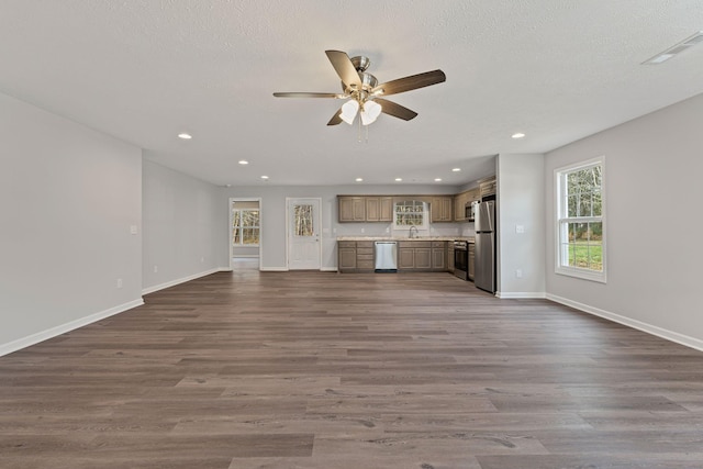 unfurnished living room featuring a textured ceiling, dark hardwood / wood-style flooring, ceiling fan, and sink