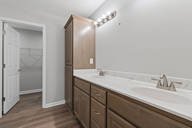 bathroom with hardwood / wood-style floors, vanity, and a textured ceiling