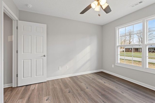 empty room featuring a wealth of natural light, ceiling fan, and hardwood / wood-style flooring